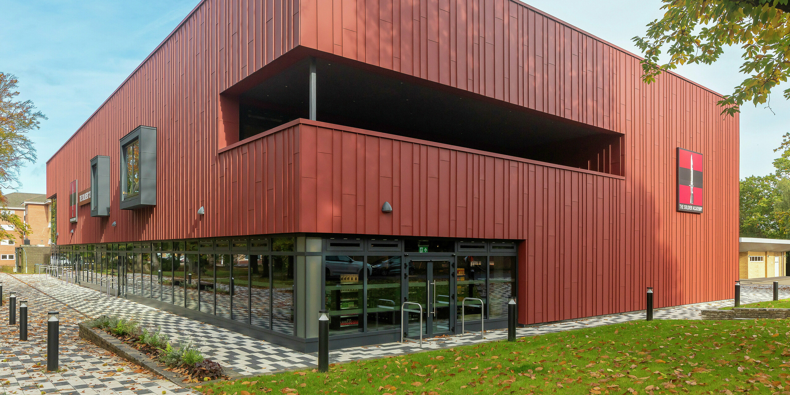 Contemporary architecture with PREFALZ: The Soldiers' Centre in Pirbright impresses with a modern standing seam façade made of PREFALZ in P.10 oxide red. The large-scale glazing on the ground floor creates transparency and openness, while window frames in P.10 anthracite set stylish accents. A sustainable construction concept with long-lasting PREFA aluminium products for the highest design and quality standards.
