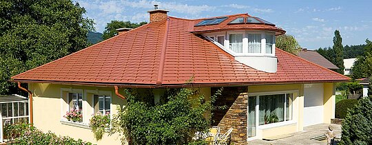 Detached house with hipped roof and dormers with PREFA brick red tile-effect aluminium shingles.