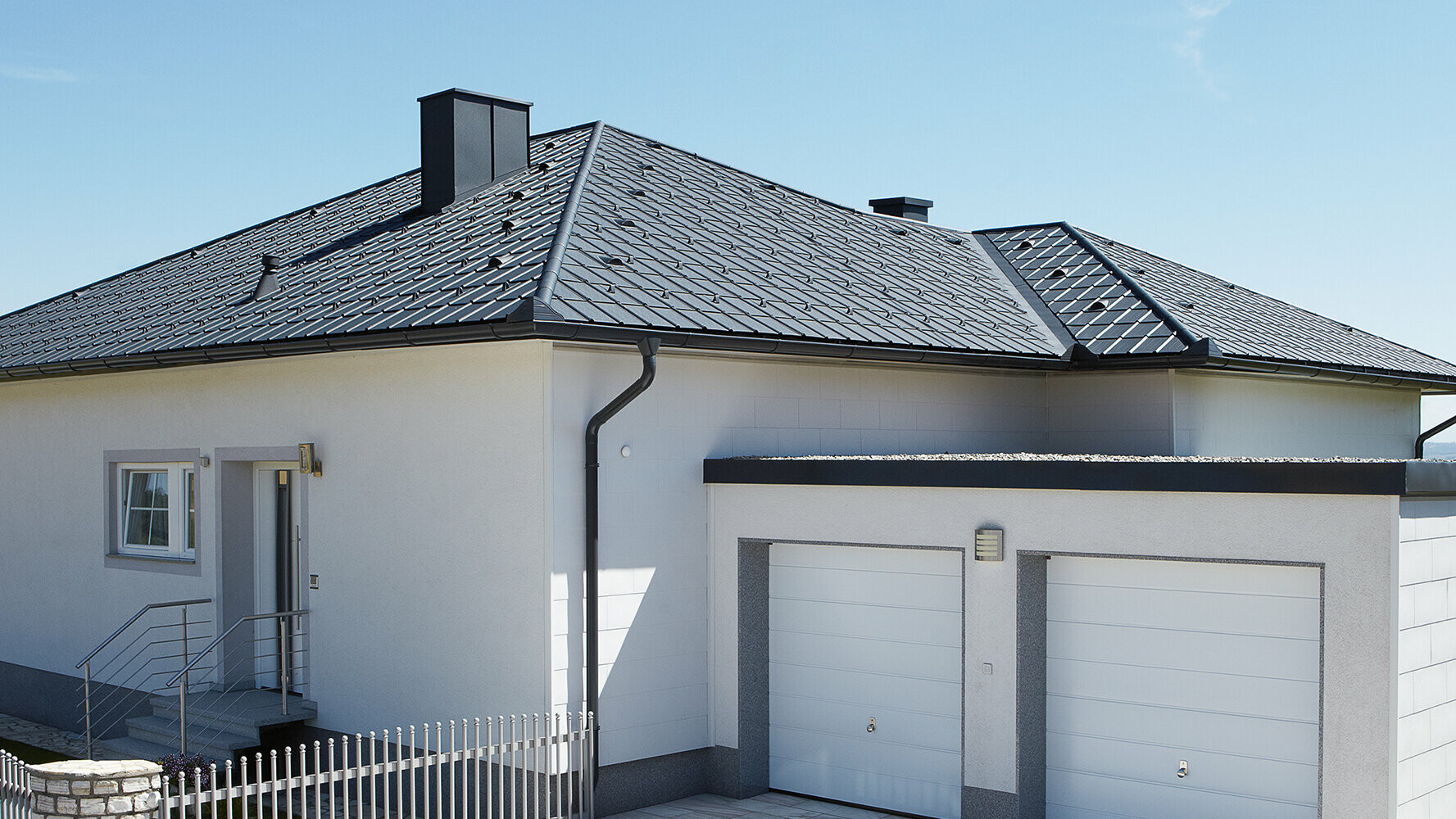 Renovated bungalow with hip roof and PREFA roof tile in anthracite  . A double garage stands next to it.