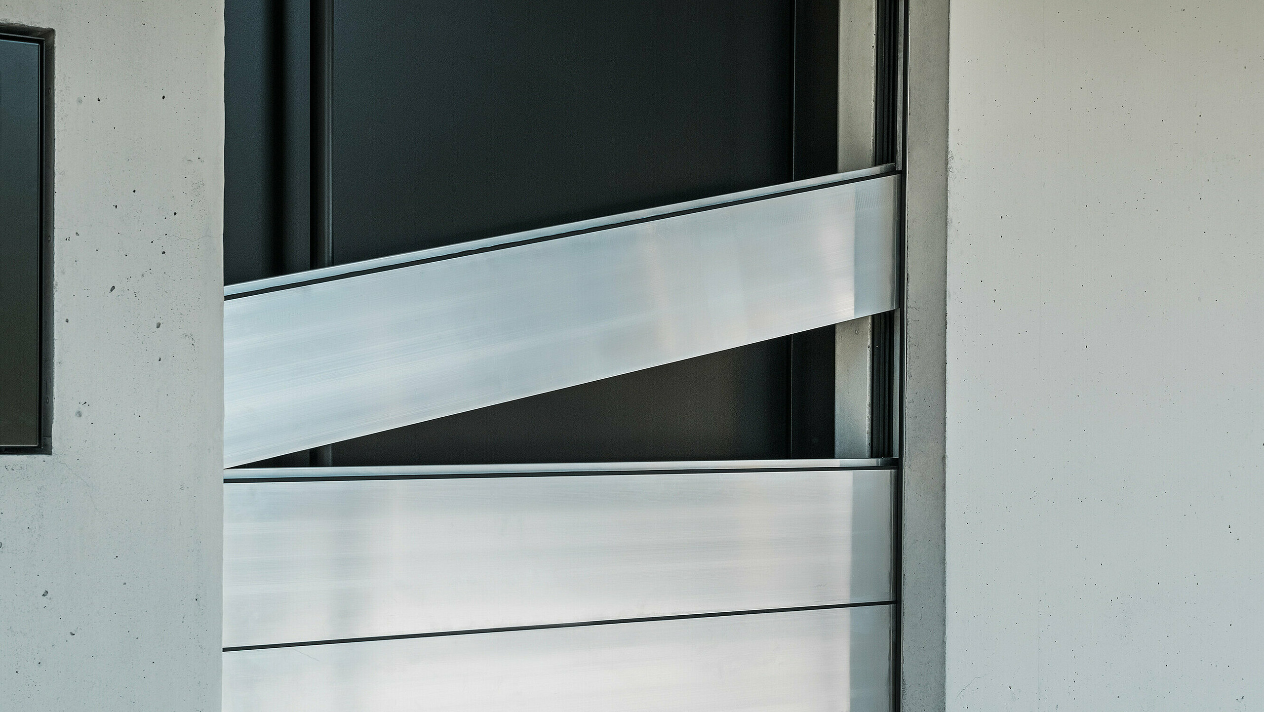 Detailansicht der Verbindungselemente des PREFA Hochwasserschutzsystems. Die innovative Technik sorgt für eine sichere Abdichtung der Haustür und schützt effektiv vor Hochwasser. Die Dammbalken werden schräg eingeschoben, wie am oberen Element deutlich zu erkennen ist.