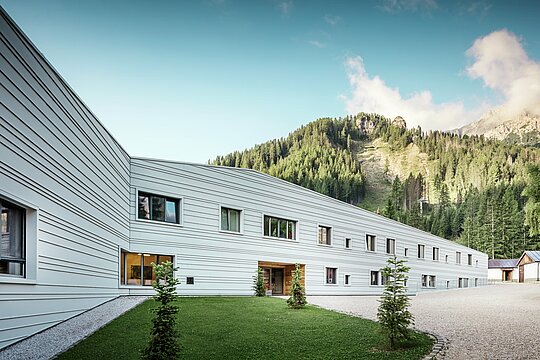 Aluminium meets precision – a harmonious dialogue between technology and nature. Against the impressive backdrop of the Dolomites, the ‘Villaggio Alpino Tempesti’ presents itself with clear lines and modern design. The façade made of PREFALZ in the colour P.10 PREFA white is not only extremely resistant, but also ensures a pleasant microclimate thanks to its light colour, as it reflects the sun's rays. Green spaces and wooden elements in the entrance area of the military building create a surprisingly inviting atmosphere.