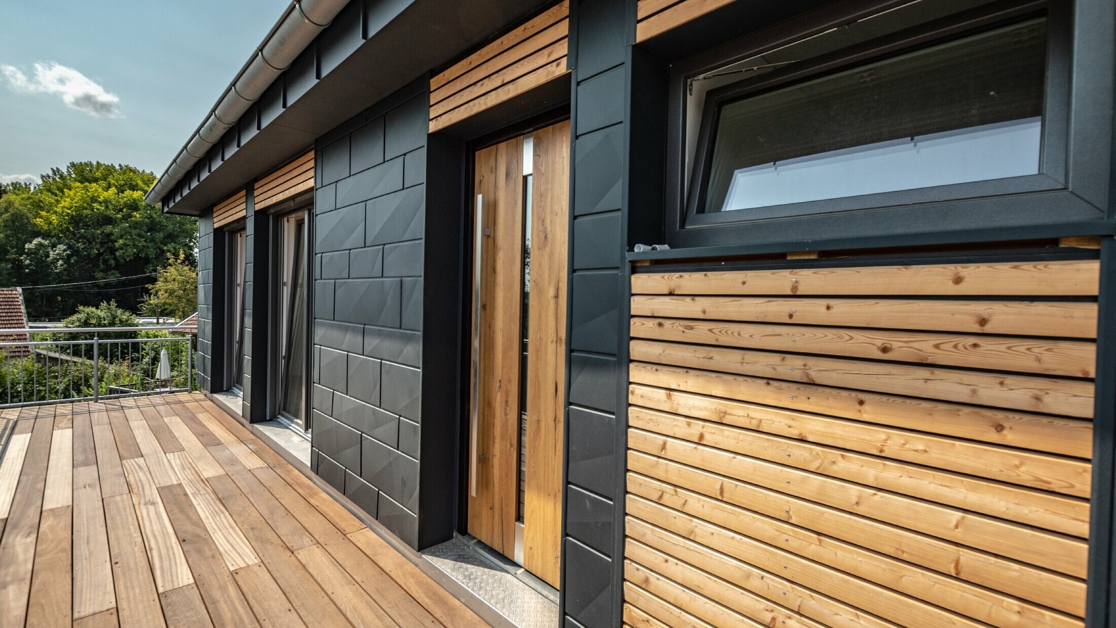 Façade design by mixing aluminium – PREFA Siding.X in anthracite – and horizontal wooden slats.