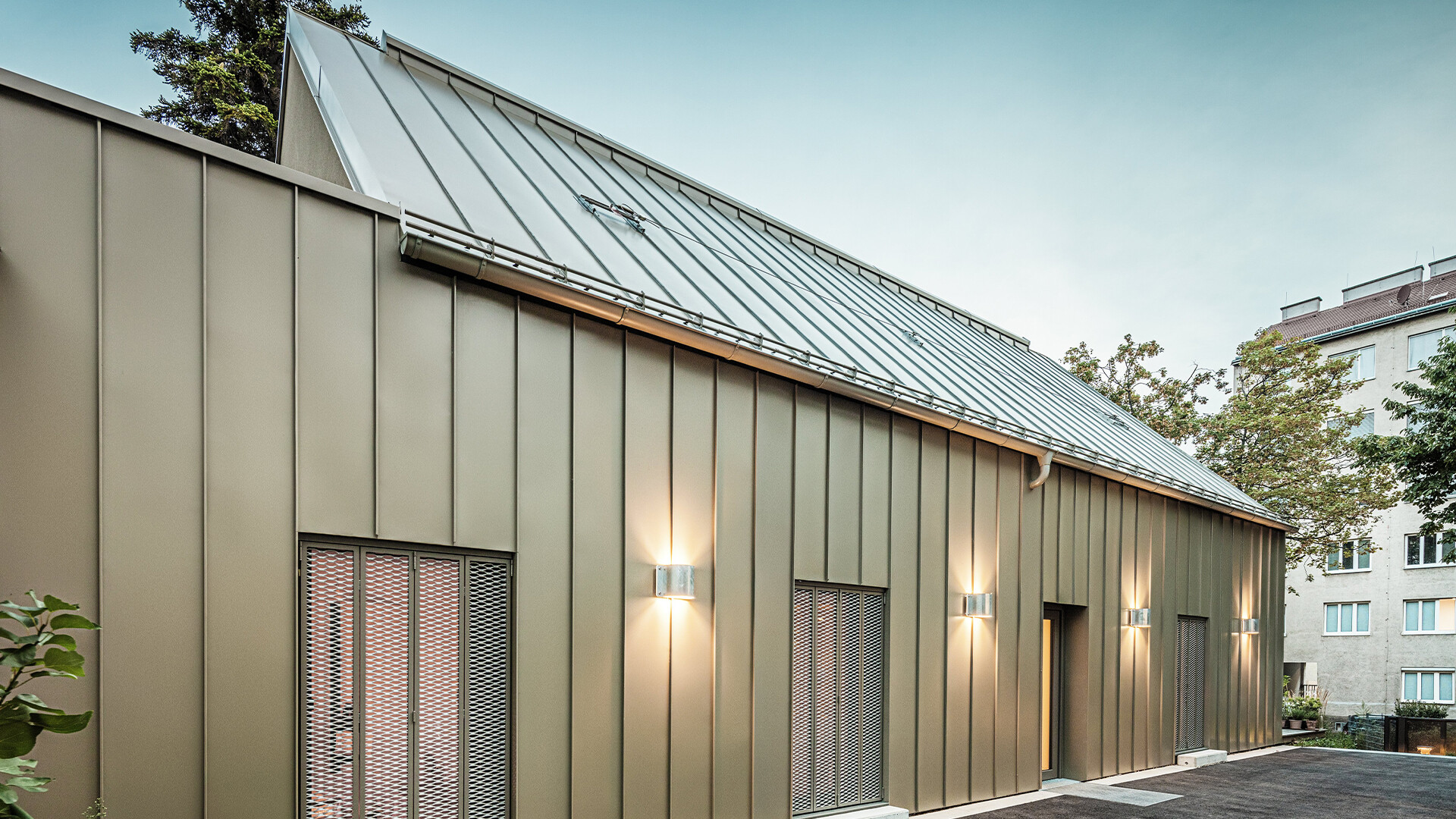 The picture shows a close-up of the Atelier Comploj with a façade and roof made of PREFALZ standing seam in the colour P.10 Prefa bronze.