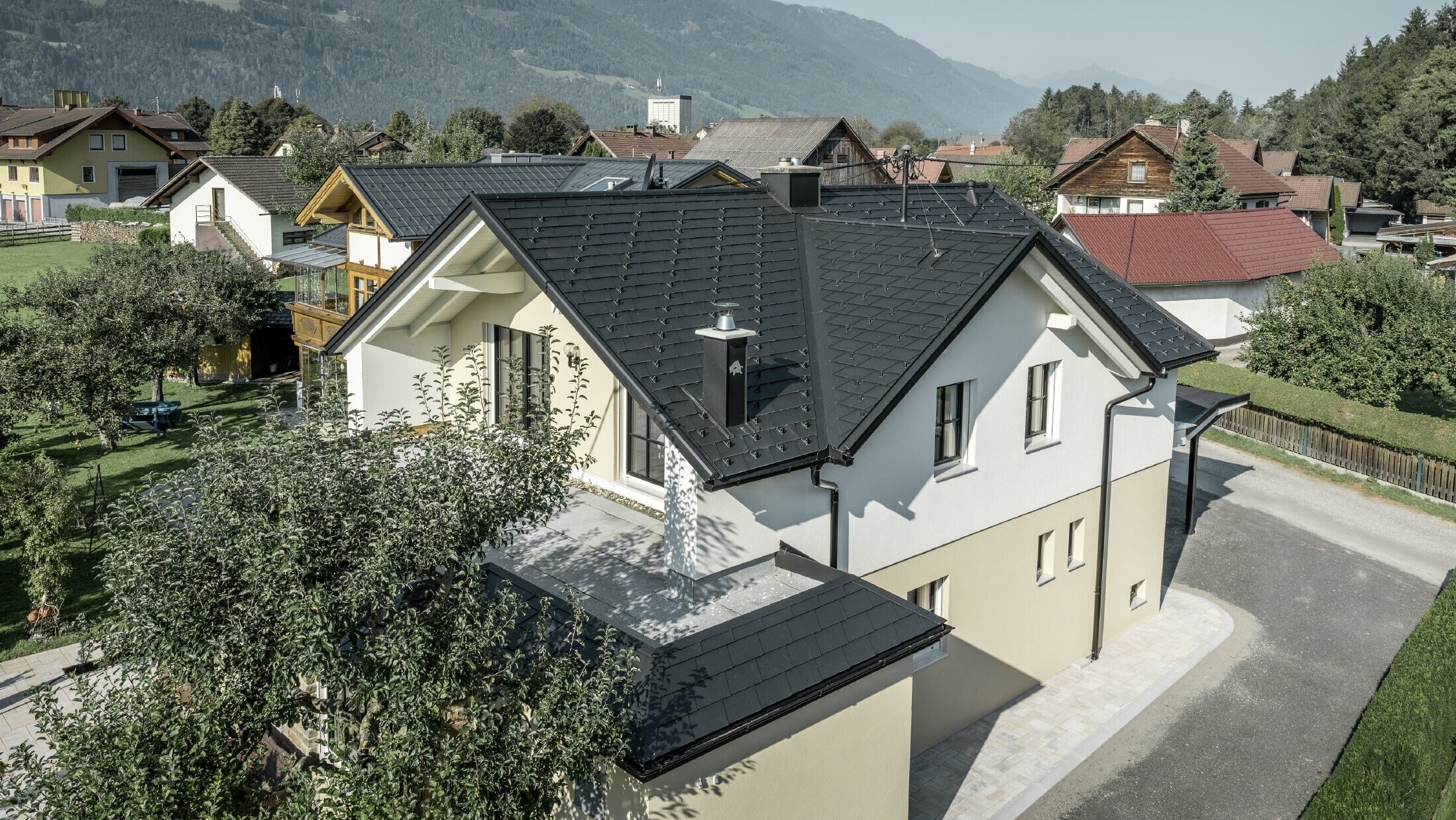 Traditional detached house with gabled roof and large dormer window, newly renovated. The roof is covered with black shingles from PREFA.