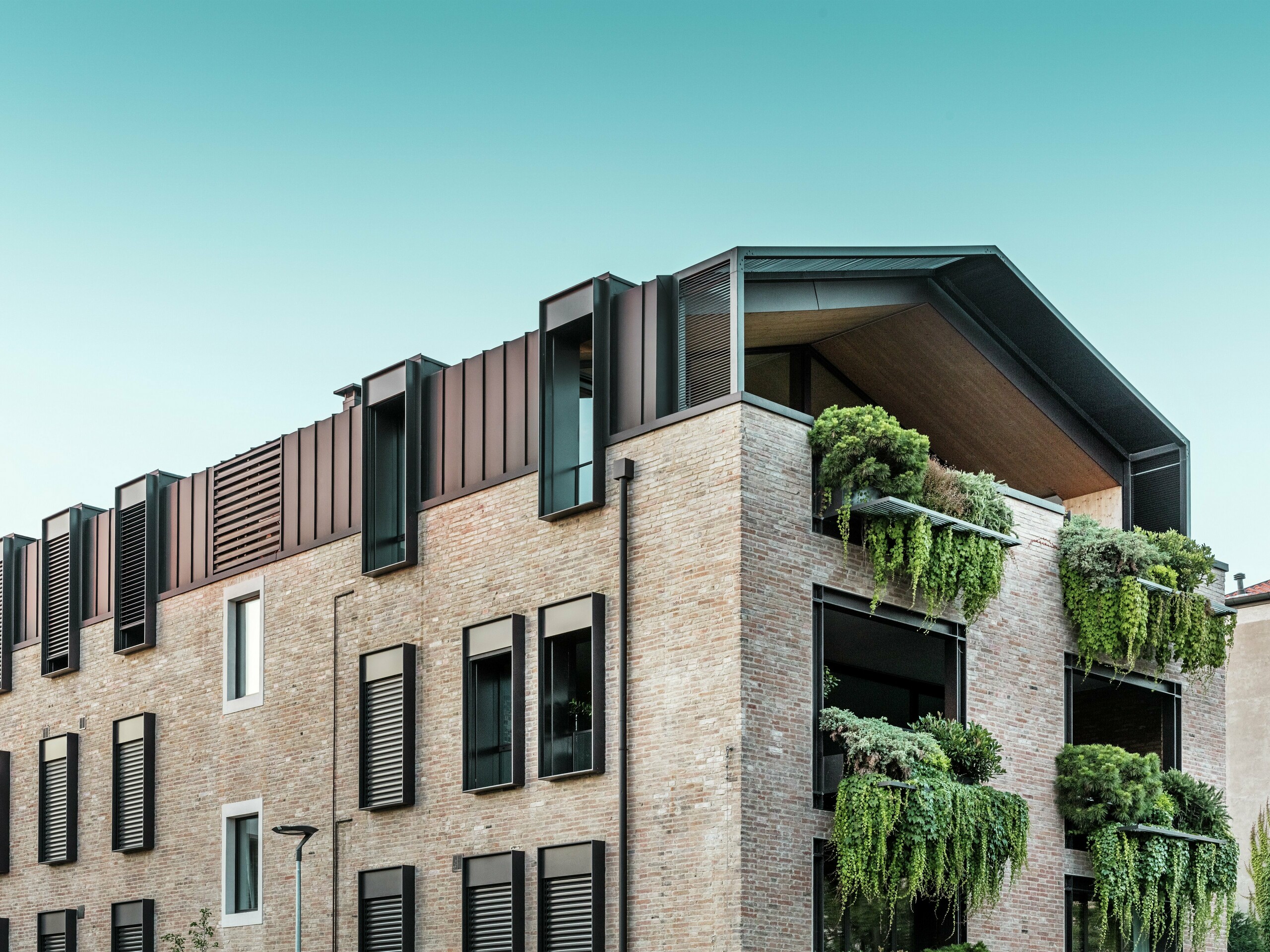 Nachhaltiges Wohnhaus in Italien mit PREFALZ-Aluminiumdach in P.10 Haselnussbraun und hängenden Gärten an der Südfassade – klimaaktive Architektur mit Ziegeln und Grünflächen.