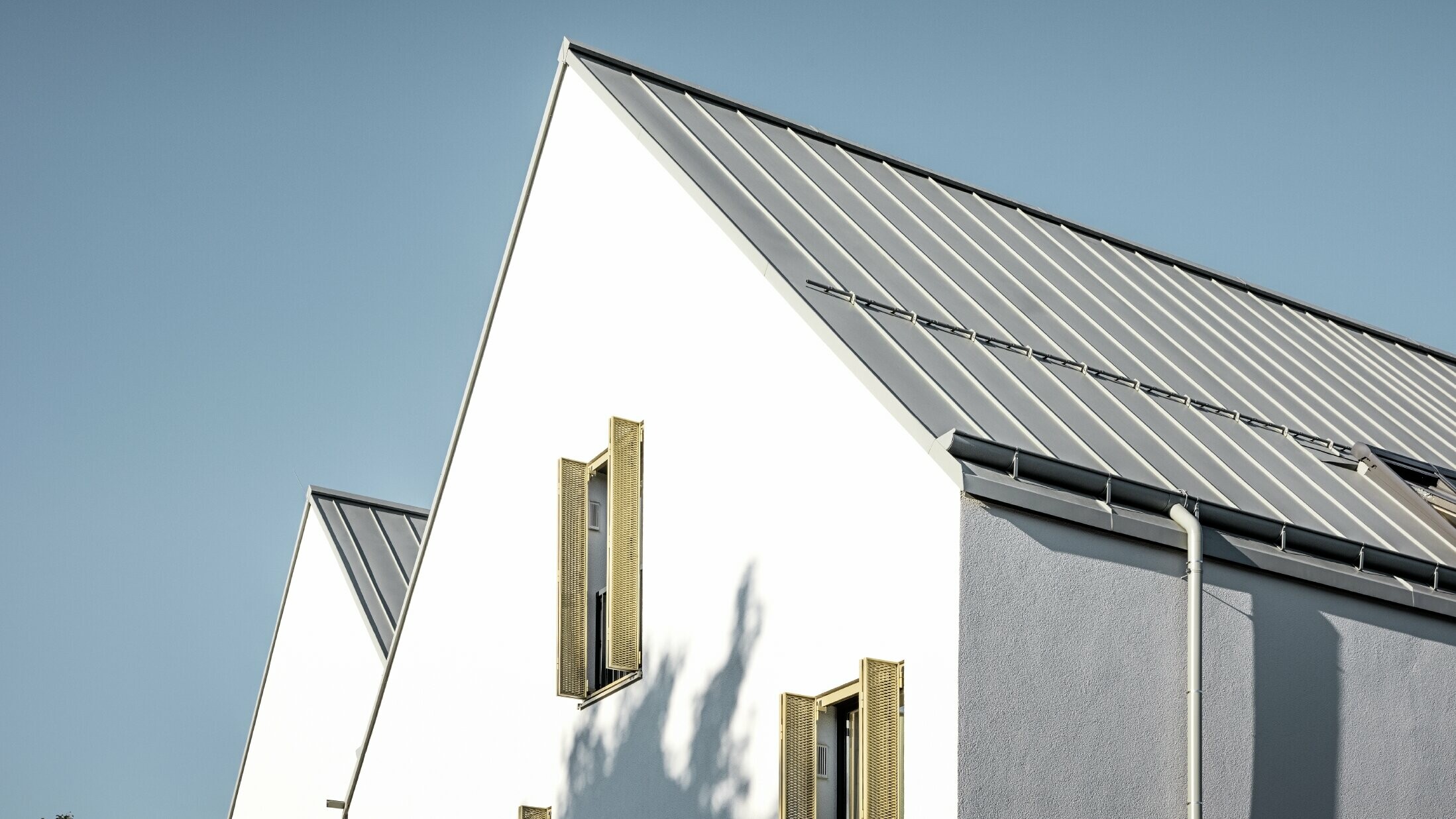 Gable roof without eaves, covered with PREFALZ standing seam in P.10 zinc grey with PREFA on-roof gutter
