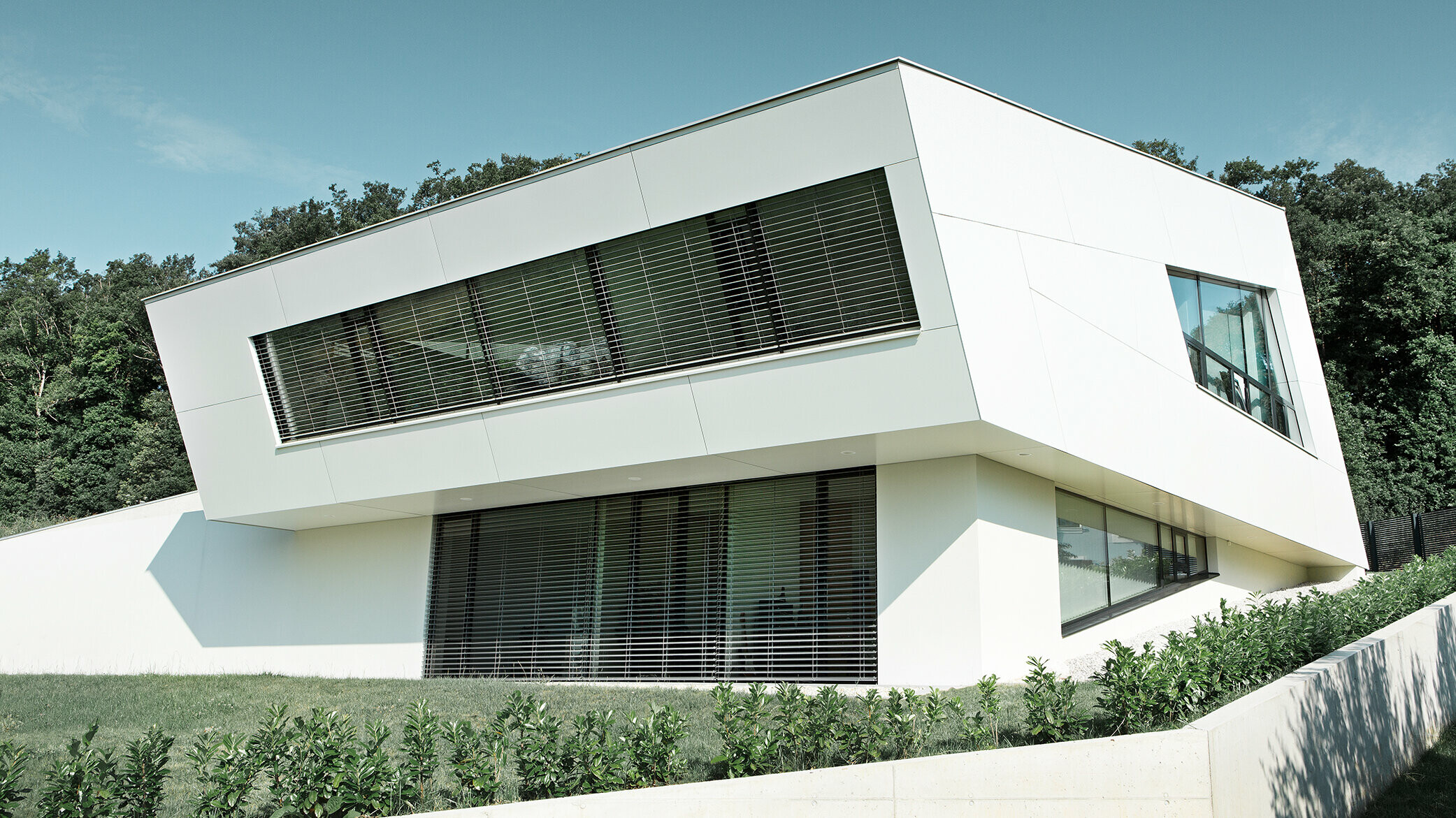 Very modern detached house with a white PREFA composite panel façade and large windows
