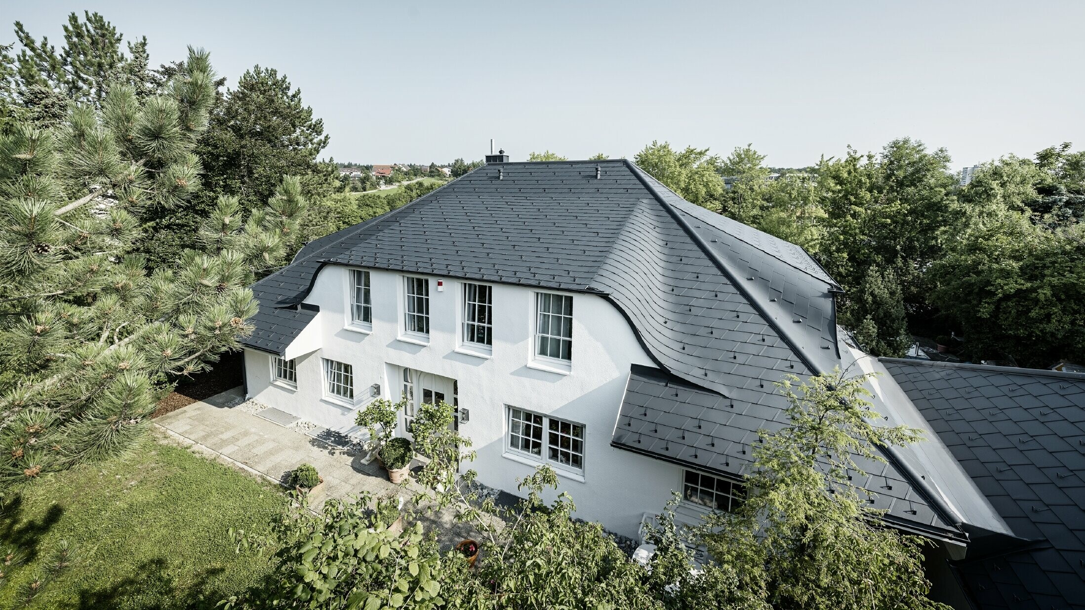Hipped roof with many curved dormers, covered with DS.19 aluminium roof shingles in anthracite