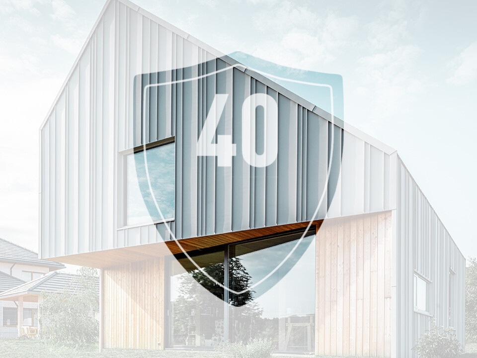 The picture shows a sign with the number ‘40’, which is supposed to represent the guarantee on PREFA aluminium products, in front of a modern detached house.