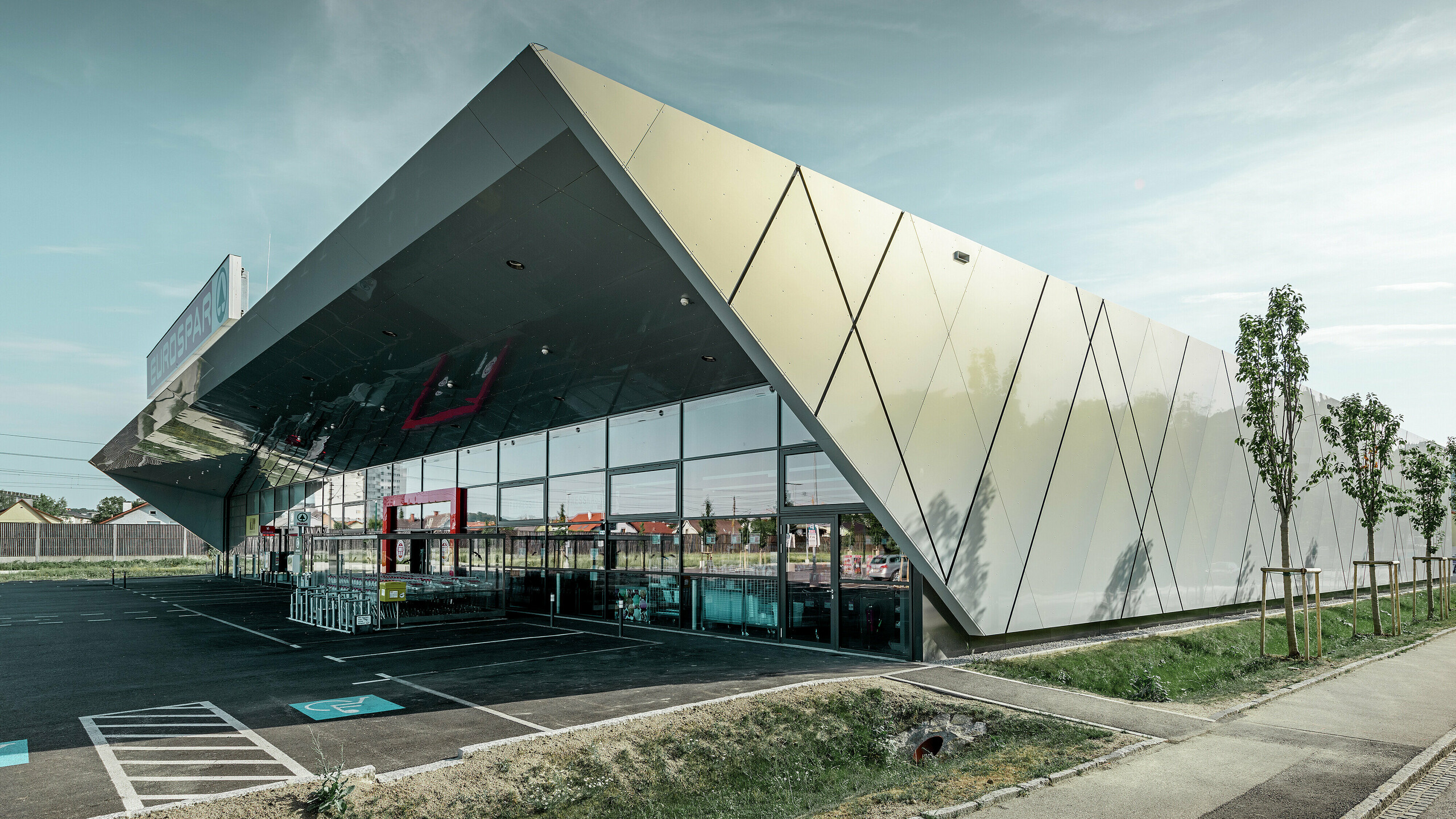 Entrance area of the new Eurospar store in Wels with a modern PREFA façade tile in silver gold. The composite aluminium tiles shimmer in different colours depending on the angle of the sun.