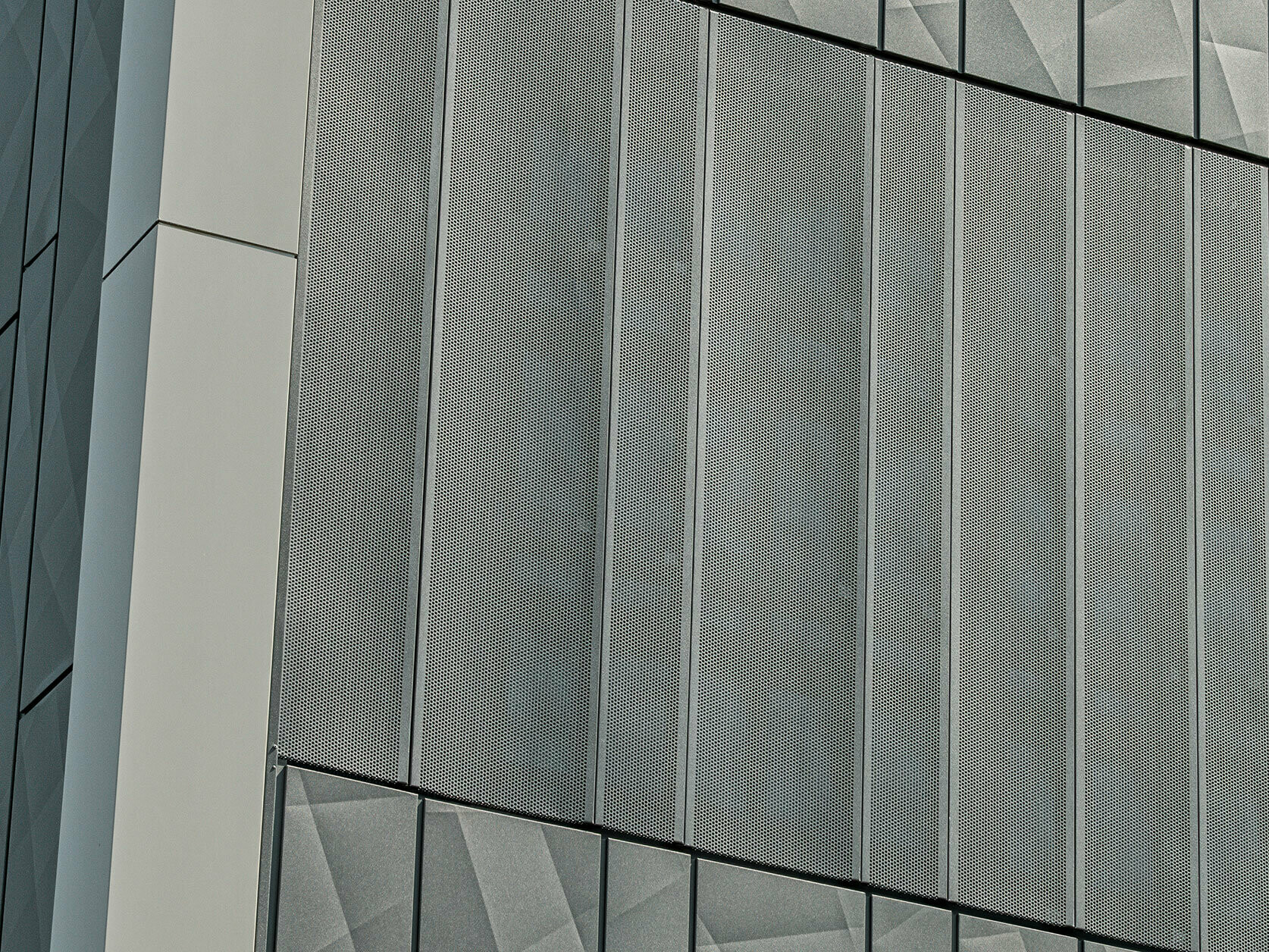 Facade view of a Eurospar supermarket in Rohrbach with PREFA Siding.X and perforated sidings in anthracite. The Siding.X elements feature a lively, geometric joint pattern, while the perforated Sidings offer a modern, air-permeable structure.