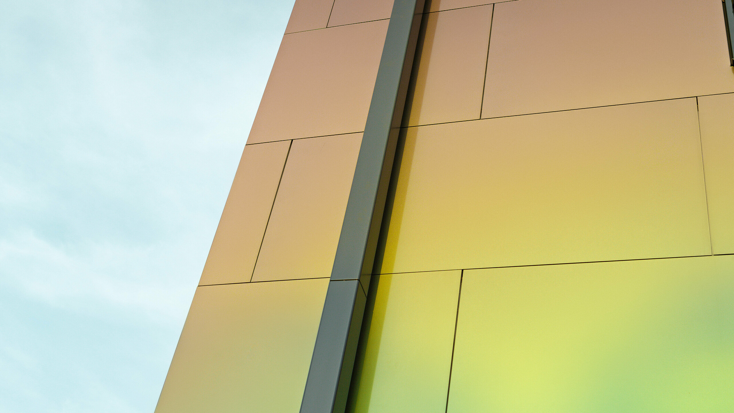 Side of a modern detached house with the modern PREFA square downpipe for draining the flat roof. The façade is clad with aluminium composite panels in the iridescent colour ‘spring lake’.
