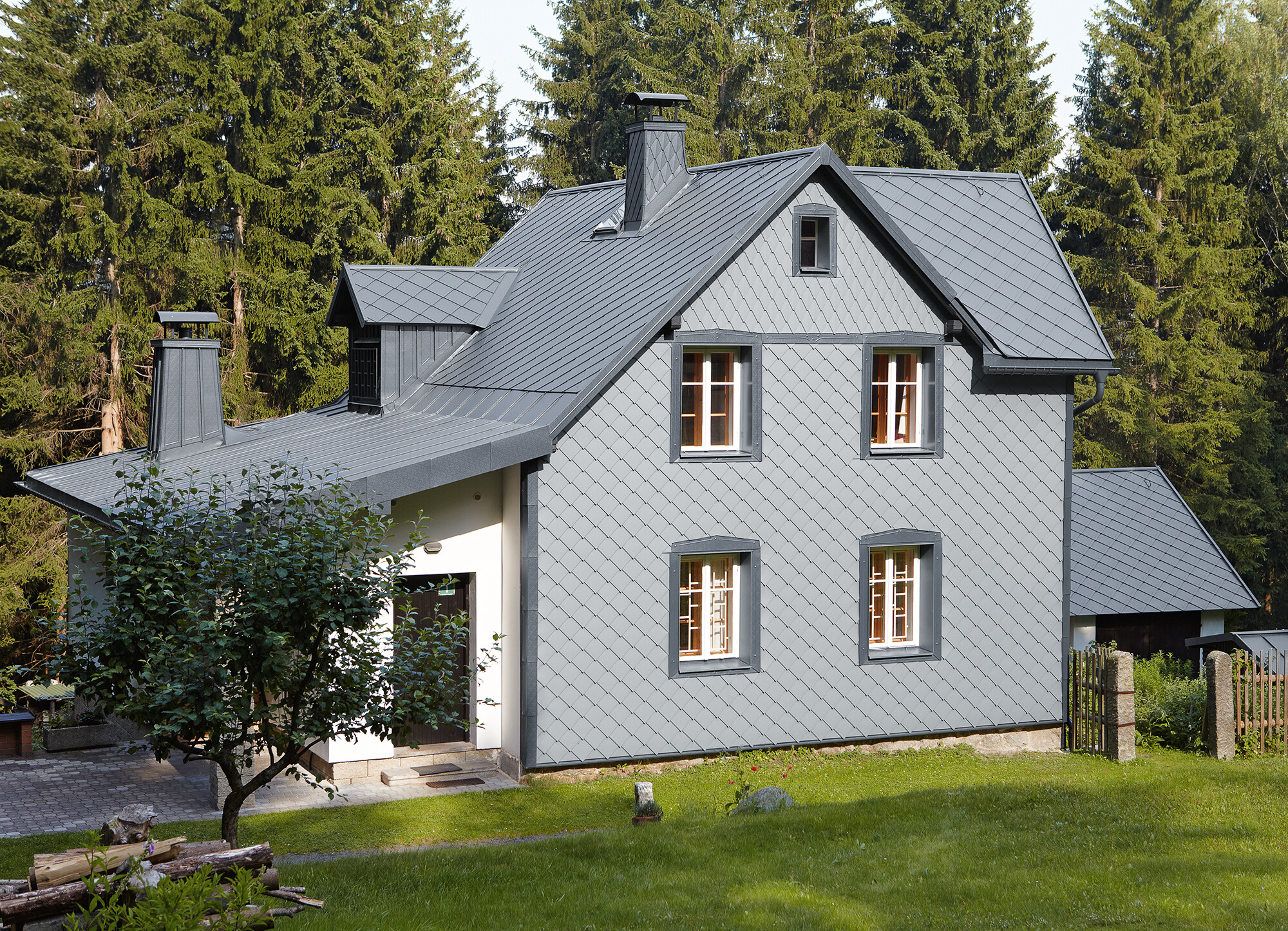 Detached house in a wooded area with a weather-resistant PREFA aluminium façade in light grey.