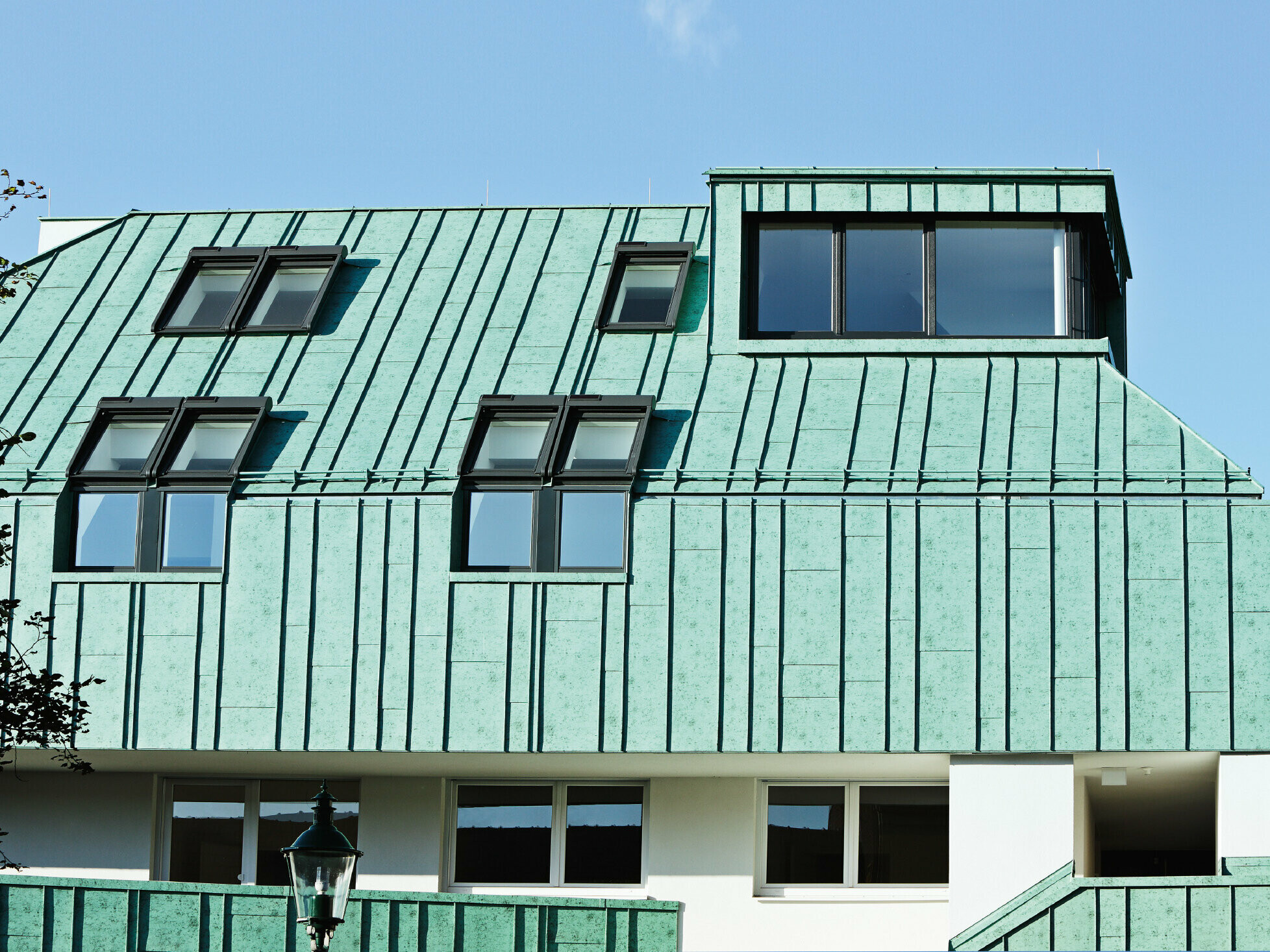 Roof and façade design with PREFALZ standing seam in patina green from PREFA in different panel widths.