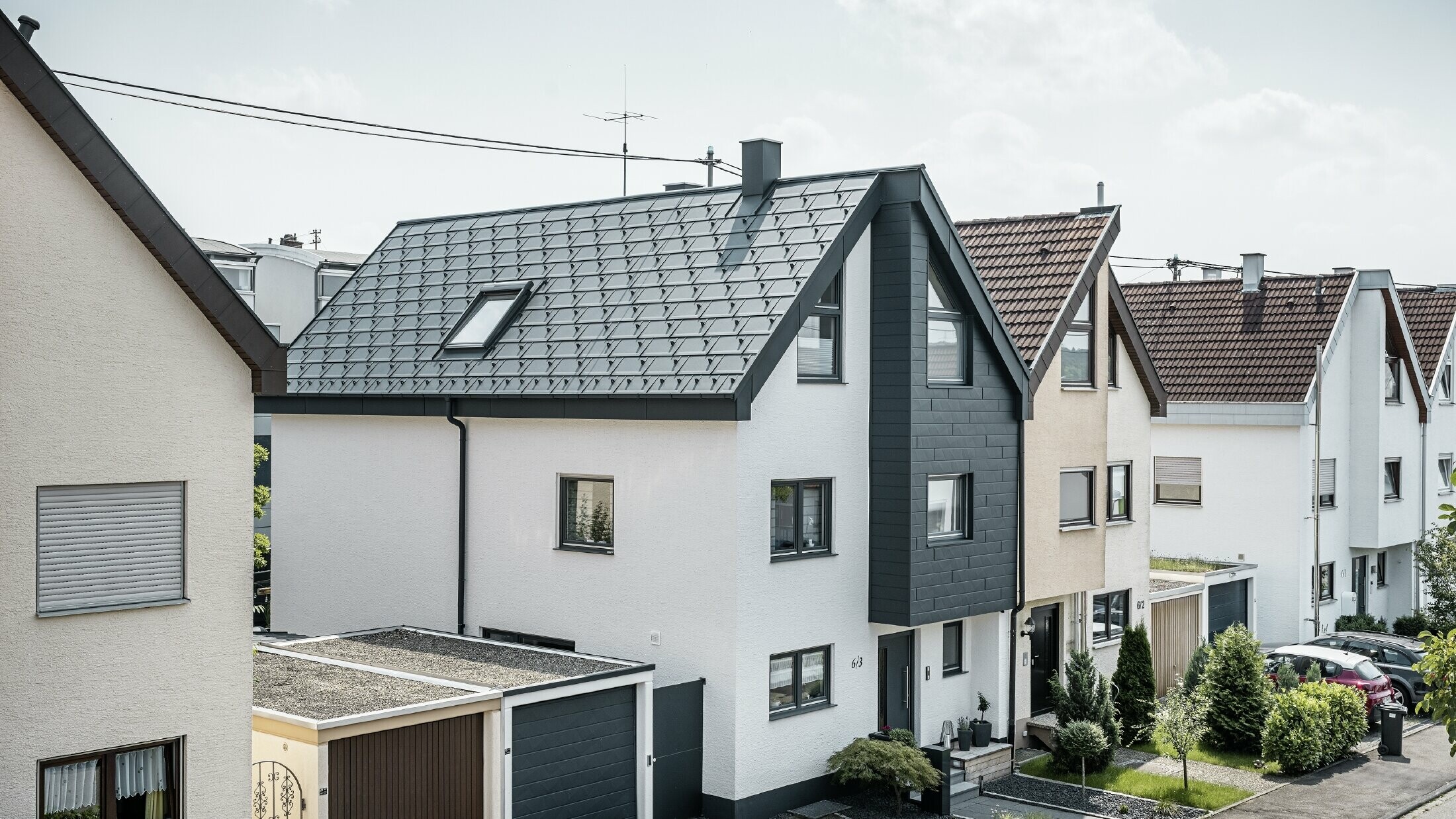 One semi-detached house has already been renovated, with a fresh white plaster façade, combined with a PREFA siding.X façade in anthracite. The roof was covered with PREFA R.16 roof tile. The roof is drained via the square box gutter and the PREFA downpipe.