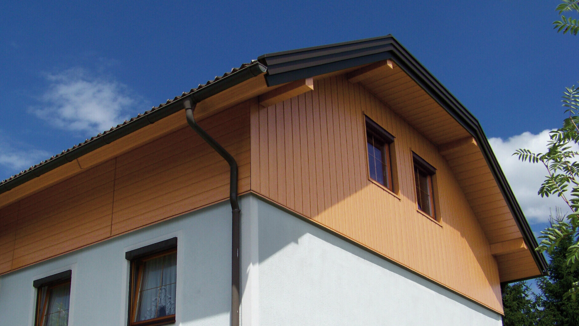 Large detached house with half-hipped roof and gable cladding using PREFA sidings in wood effect (natural oak colour)