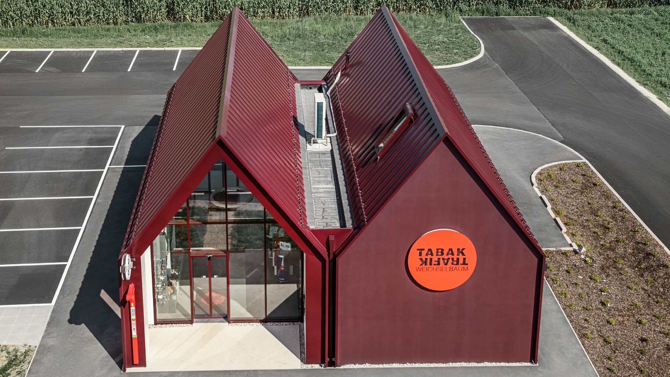 Modern tobacconist with gable roof (without overhanging eaves) and an aluminium coating by PREFA with standing and single lock standing seam in the special colour of black red